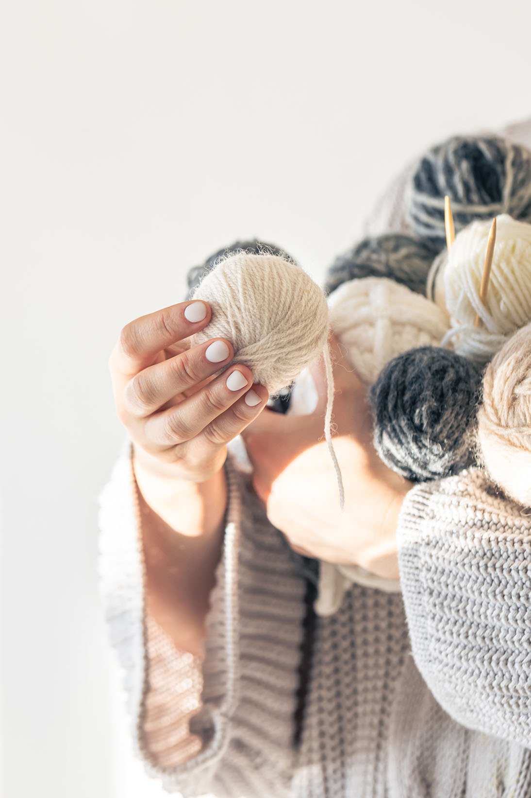 Close-up, woman hands holding several colored balls of thread.